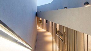 A modern architectural corridor with a curved wall and a wooden panel design. - Syvota 08 Sunset 2B Zara (Igoumenitsa)