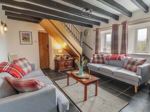 A cozy living room with a sofa, a coffee table, and a staircase leading to an upper level.