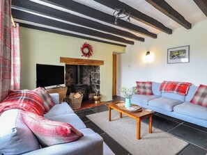 A living room with a stone fireplace, a television, and a sofa set.
