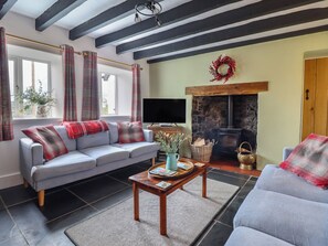 Una sala de estar con sofá, mesa de centro, chimenea y televisión.
