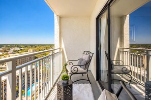 A balcony with a chair, a small plant, and a white furry rug. - Oceanview Luxe | Sea Mist Fifty-One Five Oh One (Myrtle Beach)