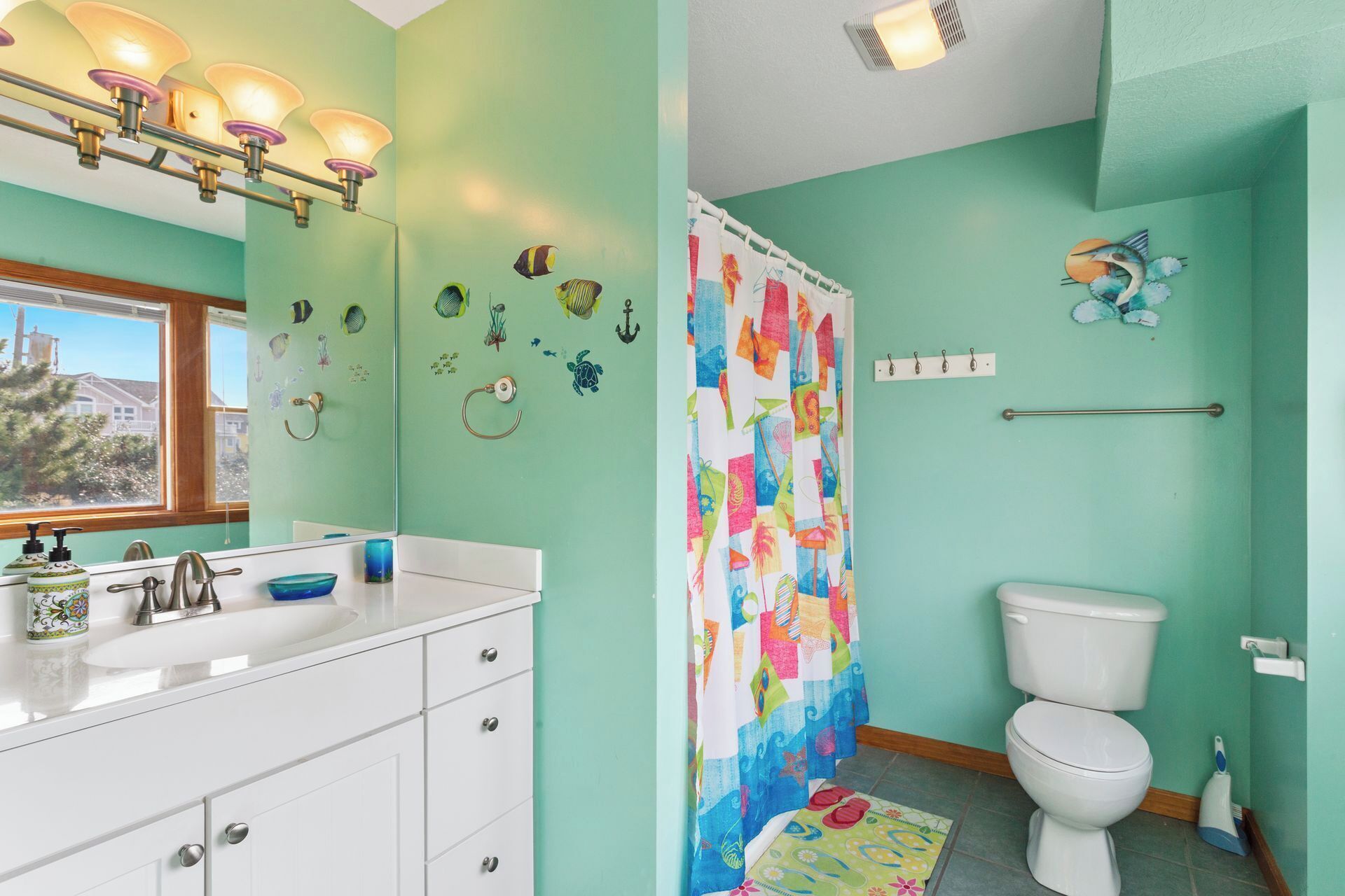 A bathroom with a white sink, a toilet, and a shower curtain with a colorful pattern.