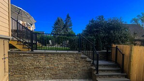 Ein Wohnbereich im Freien mit einer Steinmauer, einem Holzzaun und einer Treppe zu einer Terrasse.