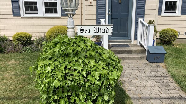 Ein Haus mit Eingangstür, Briefkasten und einem Schild, auf dem 'Sea Wind' steht.