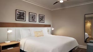 A hotel room with a large bed, two bedside lamps, a nightstand with a drawer, and three framed pictures on the wall.