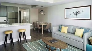 A modern living room with a grey sofa, a coffee table, and a dining area with a table and chairs.