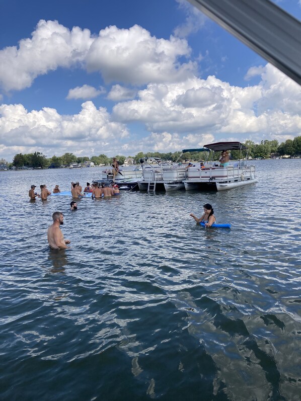 A lake with people swimming and boats docked. - Large family cottage steps from waters edge. (Pierceton)