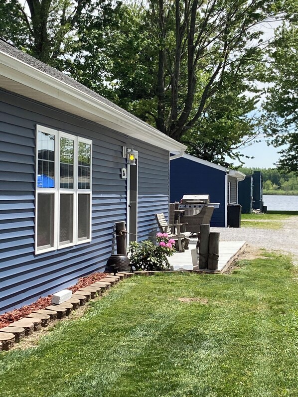A small, single-story cabin with a front porch, a grill, and a small deck. - Large family cottage steps from waters edge. (Pierceton)