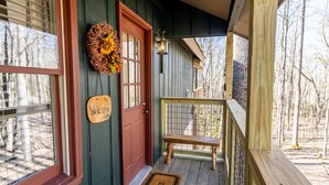 A wooden porch with a red door, a welcome sign, and a decorative wreath. - Peaceful Cabin Near Many Activities (Beech Mountain)