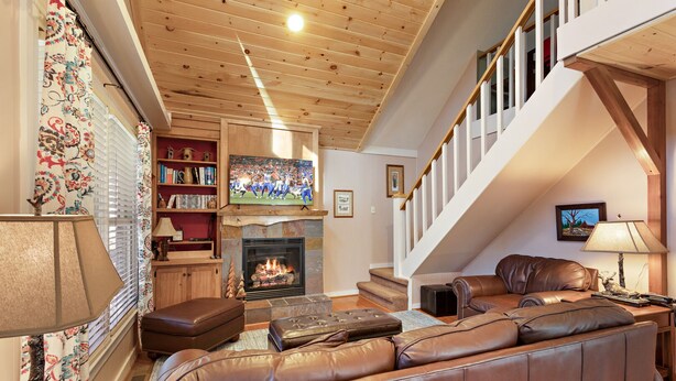 A cozy living room with a fireplace, leather sofa, and a staircase. - Peaceful Cabin Near Many Activities (Beech Mountain)