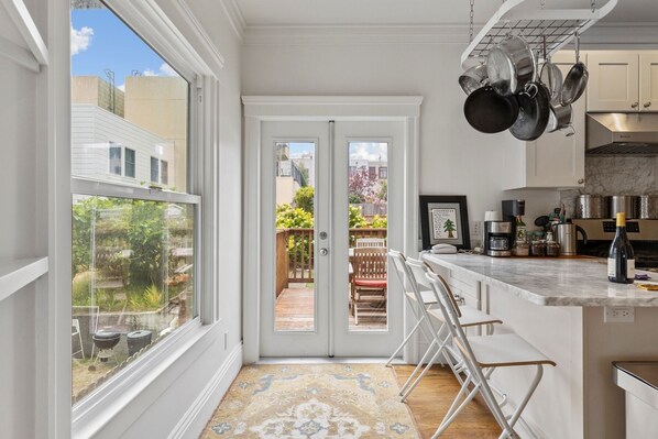A kitchen with white cabinets, a marble countertop, and hanging pots.