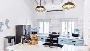 A modern kitchen with white subway tiles, stainless steel appliances, and a marble island. - Cozy cabin with océan view (Omoa)