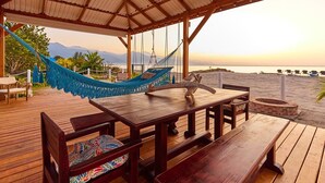A wooden deck with a table and benches, a hammock, and a view of the beach and mountains. - Cozy cabin with océan view (Omoa)