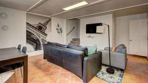 A living room with a large couch, a dining table, and a staircase leading to another level. - Hyde Park Hyde Out Apt 5 (Boise)