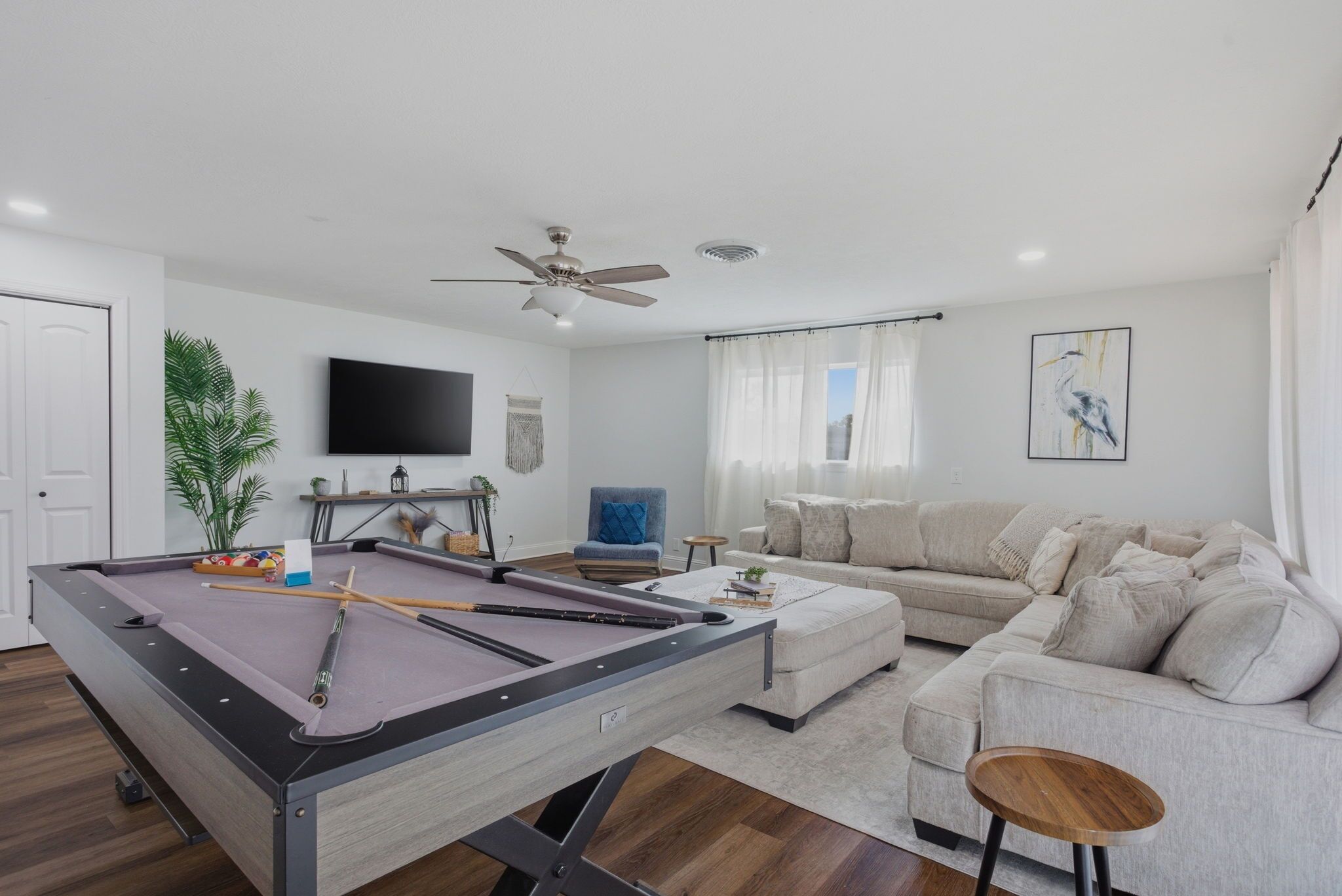 A living room with a pool table, a sofa, a television, and a ceiling fan.