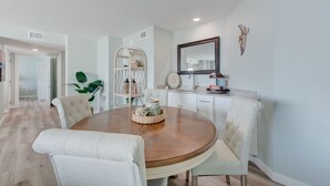 Un espace repas comprenant une table ronde en bois, des chaises à revêtement blanc et un buffet.