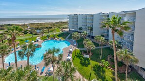 Un hôtel doté d’une piscine, de palmiers et offrant une vue sur l’océan.