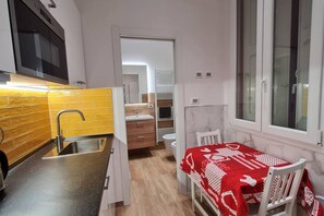 Eine kleine Küche mit Spüle, Mikrowelle und Blick auf einen Balkon.