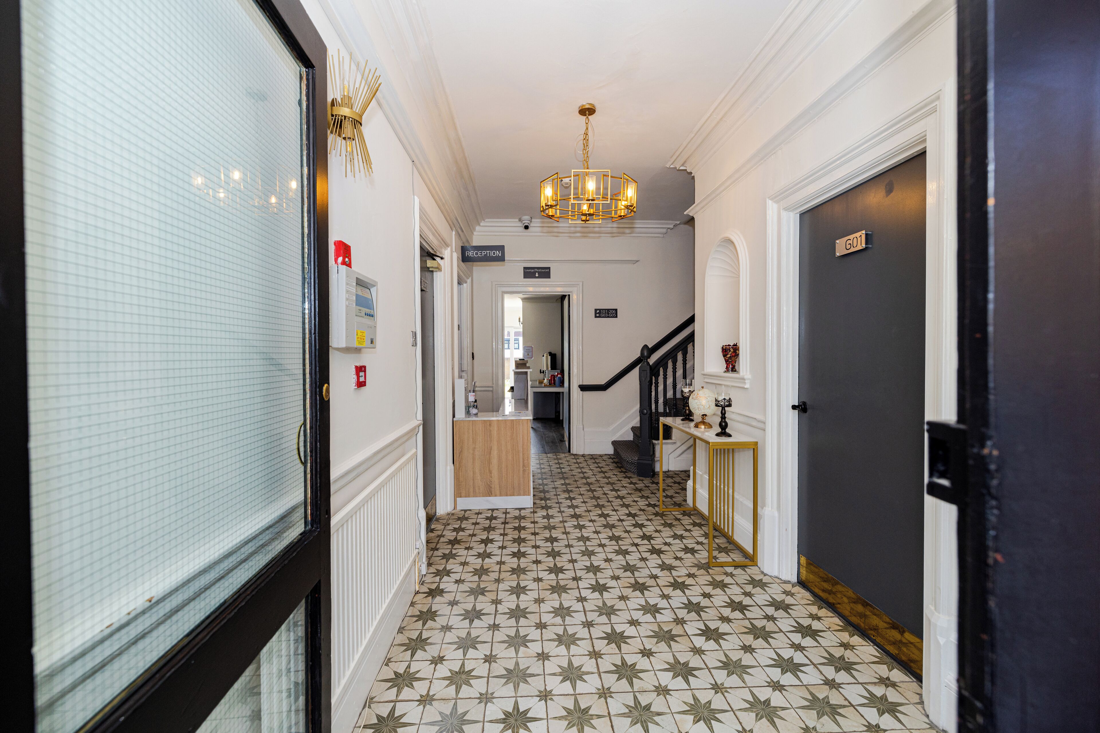 Un pasillo con piso estampado con motivos de estrellas, un mostrador de recepción y una escalera que conduce a otro piso.