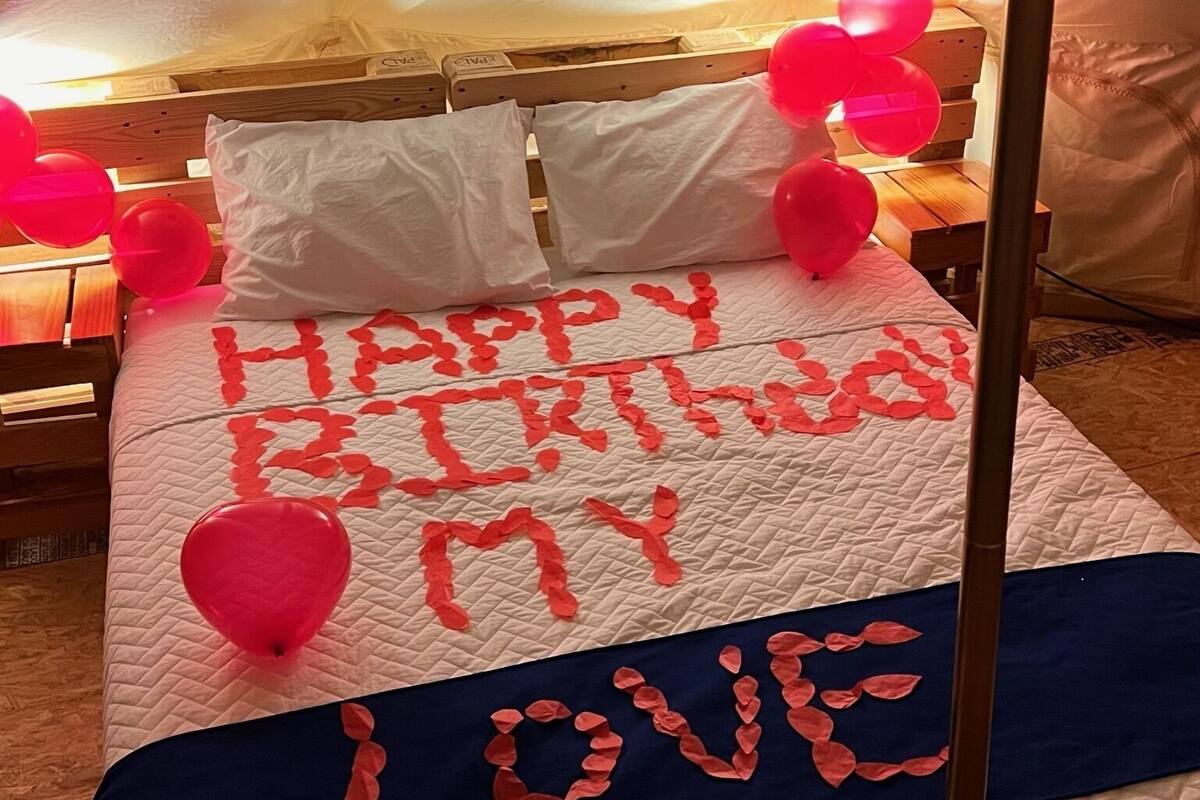 Una cama con una colcha acolchada, almohadas y falda de cama azul.