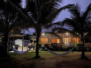 A building with a covered outdoor area, palm trees, and a hammock. - Cojimies Paradise (Cojimies)