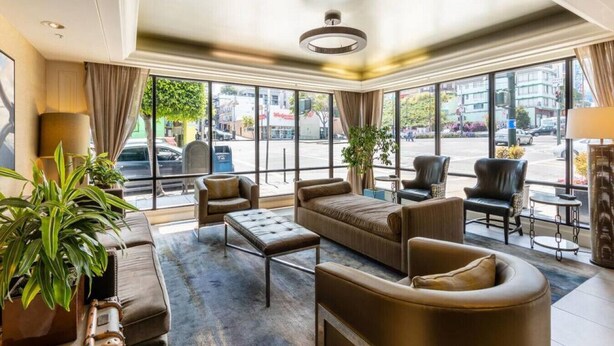 A spacious hotel lobby with leather sofas, armchairs, and a coffee table. Large windows offer a view of the street. - Marriott Vacation Club Pulse, SF (San Francisco)