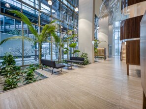 A spacious indoor area with modern furniture, large windows, and indoor plants. - Trendy Helio Tower 1BR w/ Gym & Lounge, nr metro U3, by Blueground (Vienna)