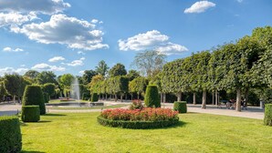 A well-maintained garden with neatly trimmed hedges, a fountain, and a variety of trees. - Refurbished Penzing 3BR w/ Elevator & Balcony, nr metro U3, by Blueground (Vienna)