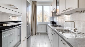 A modern kitchen with a built-in oven, a stove, a sink, and a window with a view of the outside. - Refurbished Penzing 3BR w/ Elevator & Balcony, nr metro U3, by Blueground (Vienna)