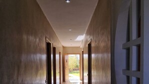 Un pasillo largo y estrecho con piso de baldosas y una gran pared decorativa a la derecha.