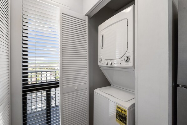 A laundry room with a front-loading washer and dryer, a window with blinds, and a door. - 2/2, Sleeps 7, Beautiful 9th floor Destin Condo on the Beach , Stunning Views!! Book now! (Destin)