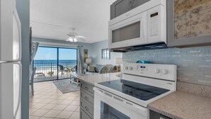 Una cocina con vista al océano, un microondas, un horno y un refrigerador.