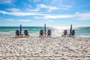 A beach with three rows of beach chairs facing the ocean.