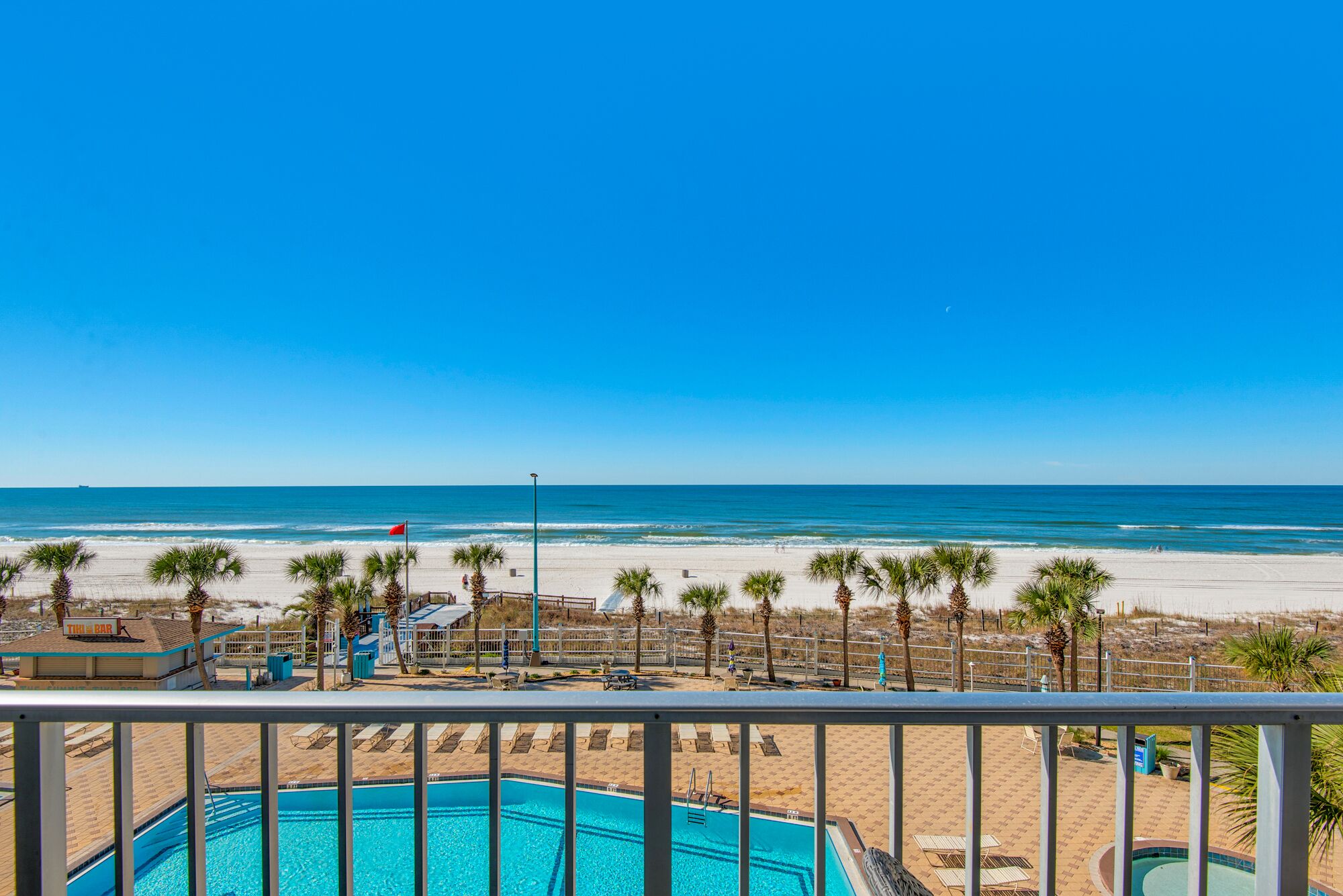 A pool area with a view of the beach and ocean.