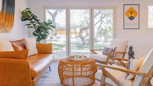 A living room with a sofa, chairs, a round wicker coffee table, and a large plant. - Sleeps 18, Ranch - Pool, Hot Tub, 2 Fire Pits (Dripping Springs)