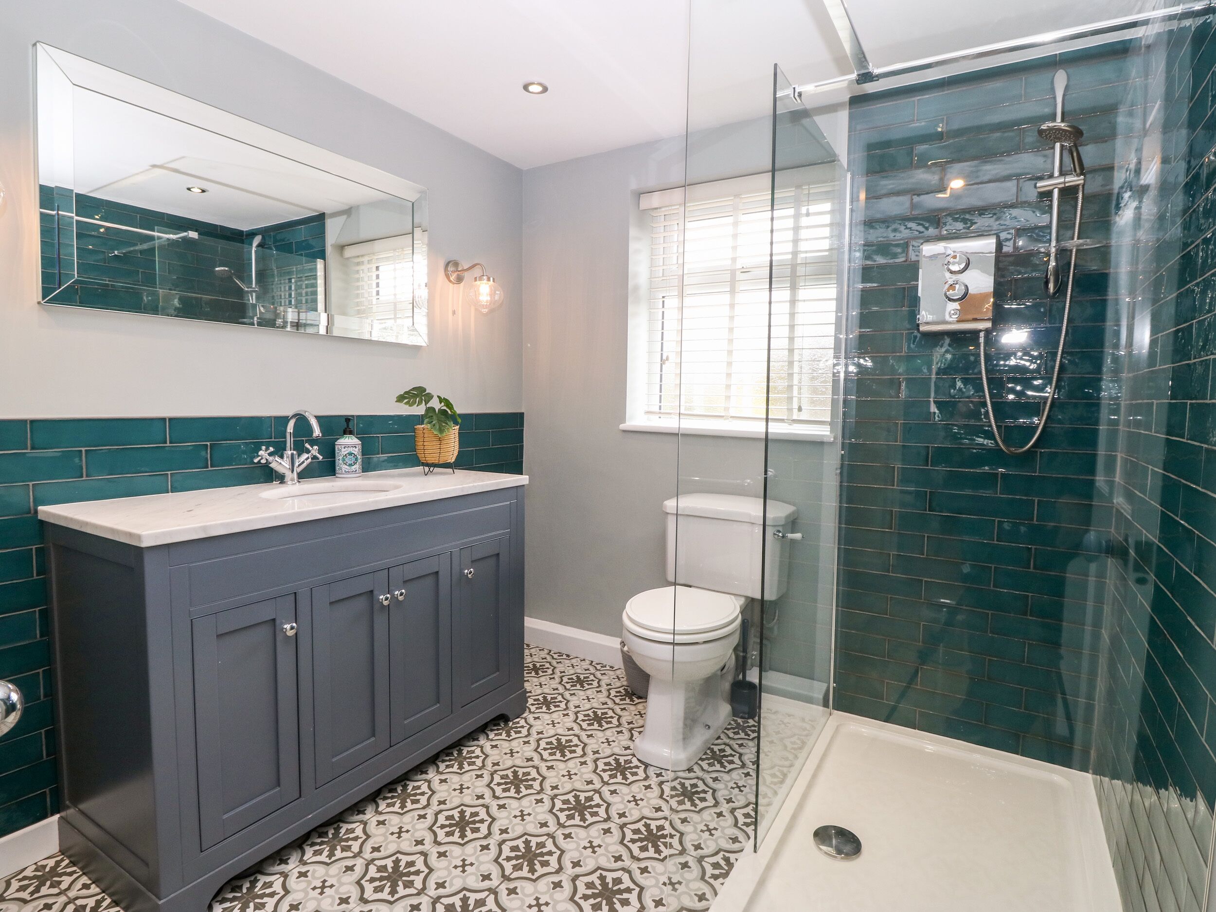 A bathroom with a glass-enclosed shower, a white toilet, and a vanity with a mirror.