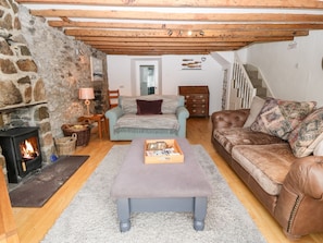 Una sala de estar acogedora con pared de piedra, chimenea, un sofá, un sillón y una mesa de centro.