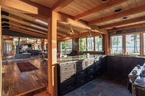 Una cocina amplia con una isla grande, vigas de madera y ventanas amplias.