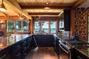 A modern kitchen with a large island, a gas stove, and a view of the outdoors. - Private Estate, Kangaroo East Shore! (Baileys Harbor)