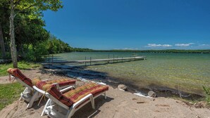 Une plage avec des chaises longues et une jetée qui s’avance dans un lac.