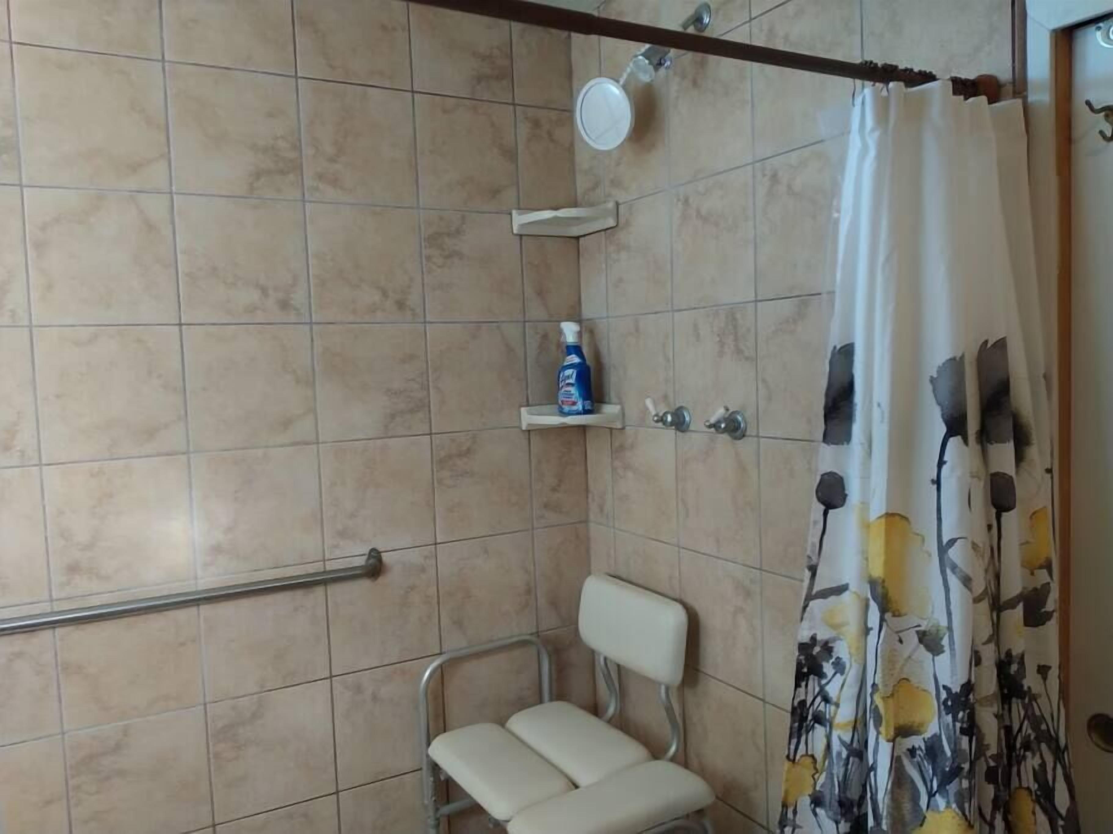 A bathroom with a shower, a toilet, and a shelf with toiletries.