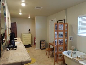 A bathroom with a sink, mirror, and a wooden rack with papers. - Studio in Pahrump | Death Valley NP (Pahrump)