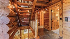 Ein rustikales Blockhaus mit einer Treppe zu einem Schlafraum darüber, Holzwänden und einem Fliesenboden.