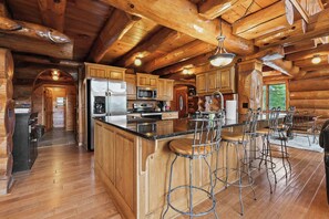 A log cabin interior with a kitchen, bar area, and wooden floors.