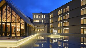 Ein modernes Gebäude mit Glasfassade, einem Innenhof mit einem spiegelnden Pool und einer Hirschskulptur.