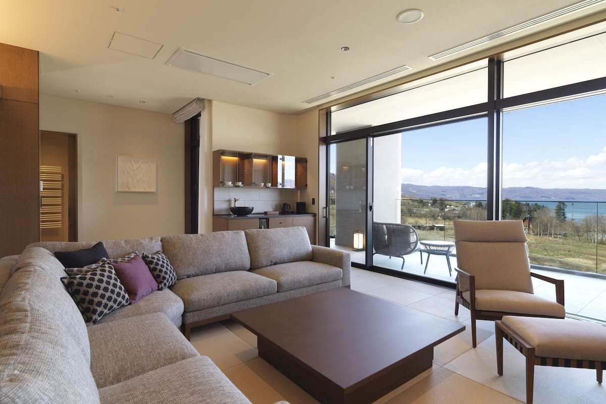 Una sala de estar moderna con un sofá seccional, una mesa de centro y vistas a un balcón con zona de comedor.
