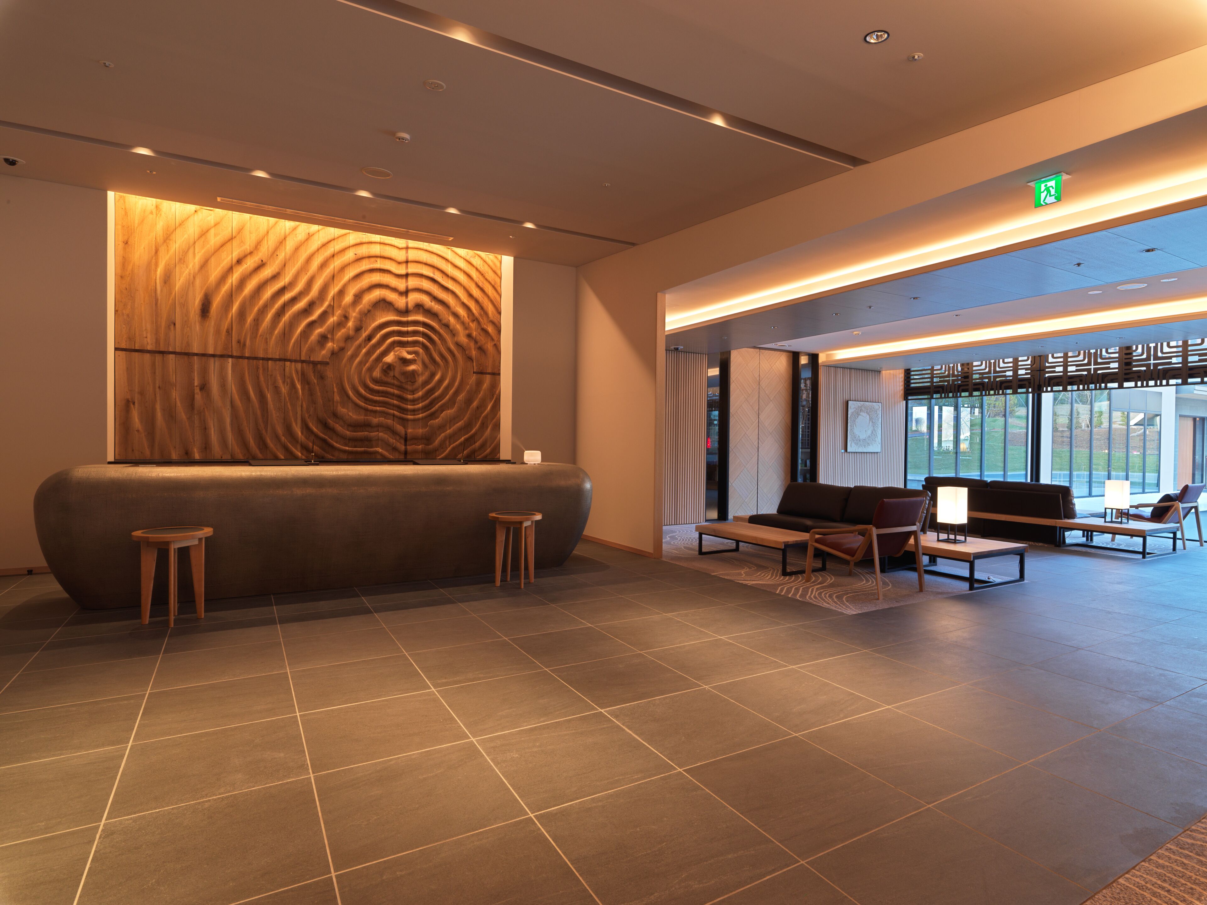 A modern reception area with a wooden wall, seating, and a view of the outdoors.