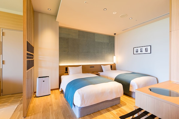 Una habitación de hotel moderna con dos camas, una mesita de noche, un escritorio pequeño y un estante en la pared.