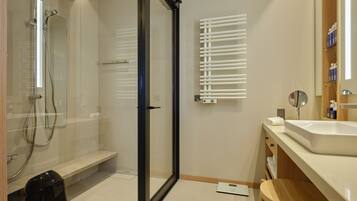 Une salle de bain moderne dotée d’une douche à parois de verre, de toilettes intégrées, d’un lavabo et d’un miroir.