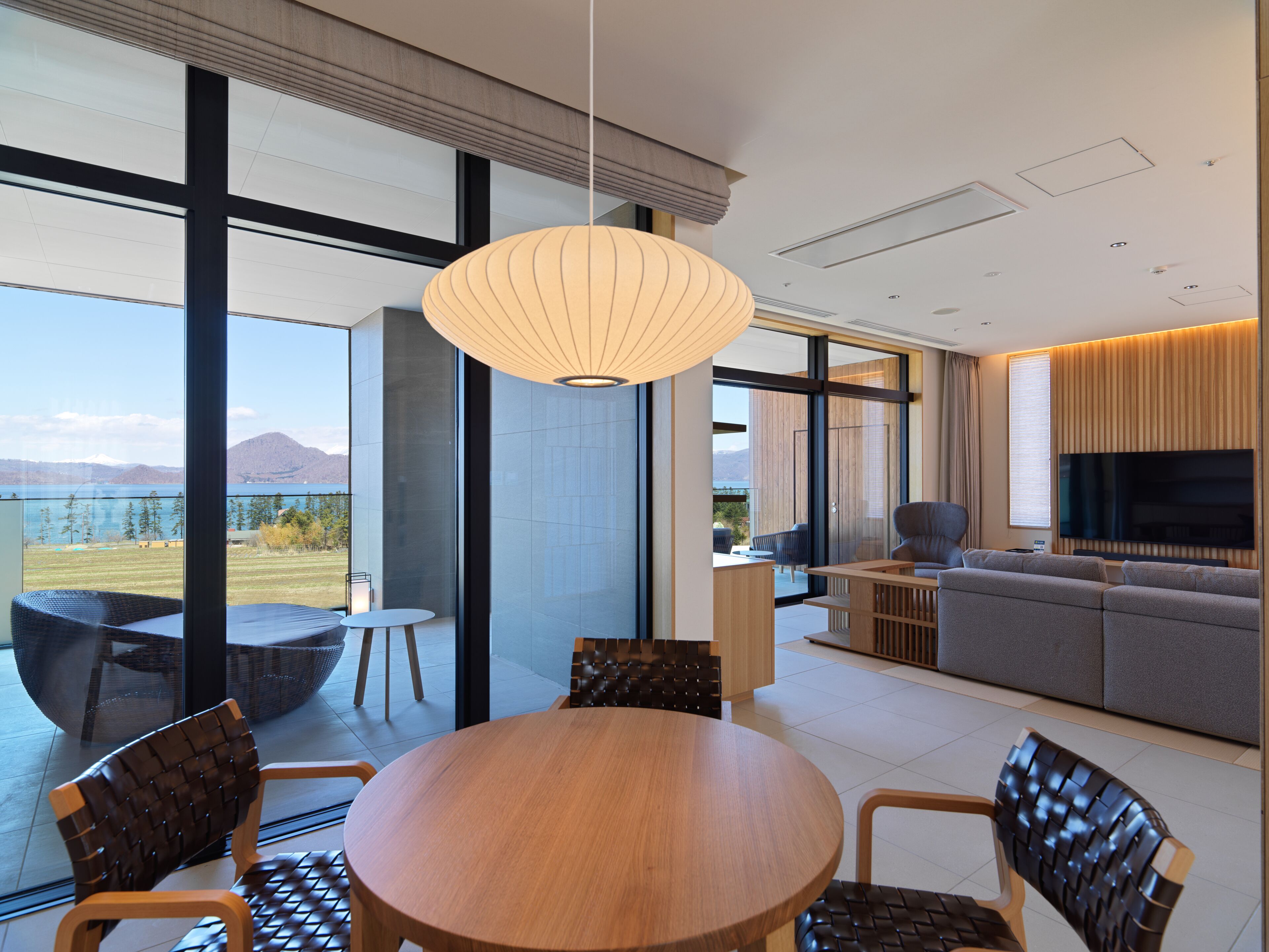 A modern living room with a large TV, comfortable seating, and a view of the outdoors.